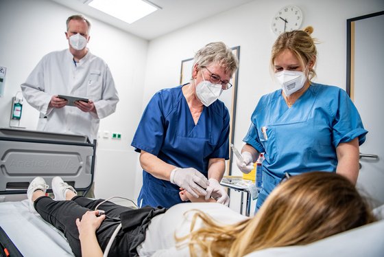 Behandlungs-Situation einer Patientin mit 2 Pflegekräften und einem Arzt 