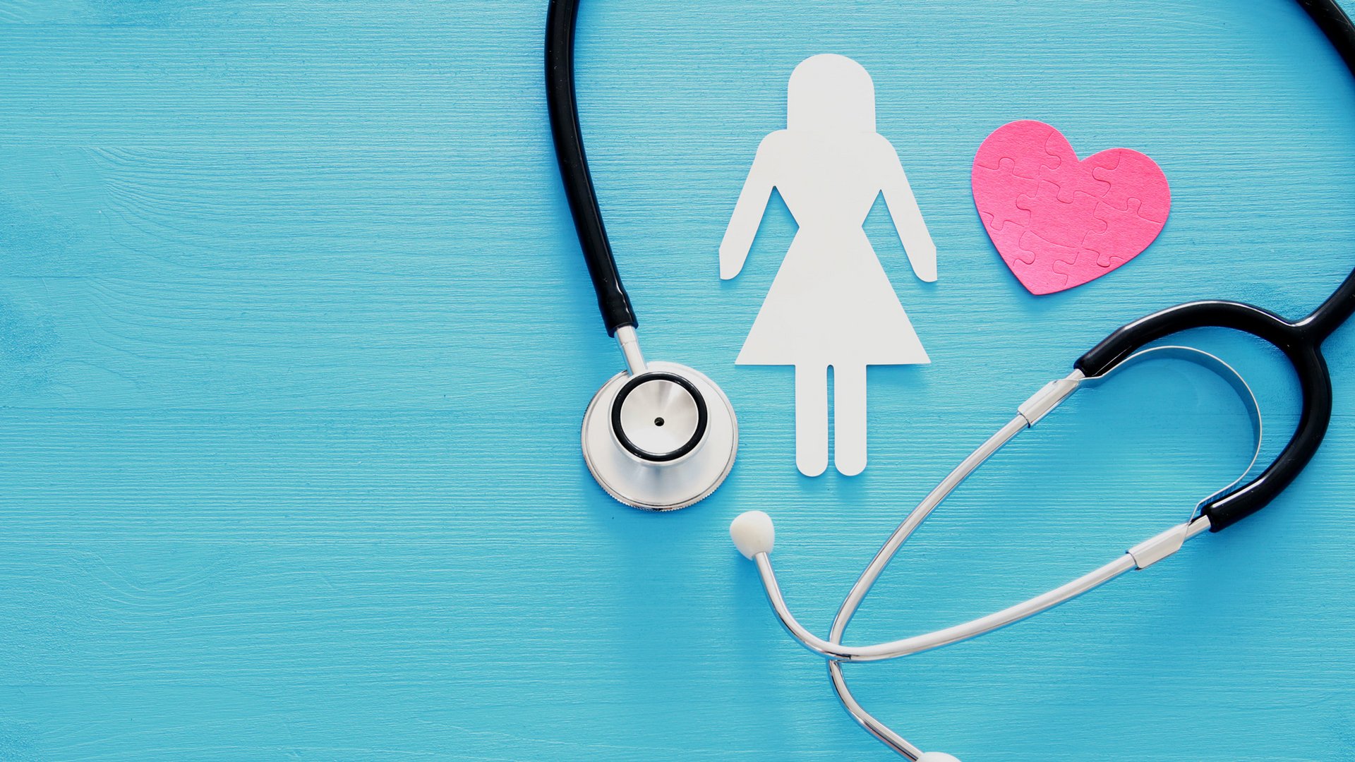 Stethoskop, eine ausgeschnittene Frauenfigur und ein Herz auf blauem Untergrund
